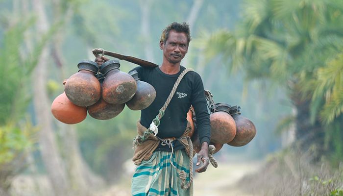 শীতের সকালে রসের হাঁড়ী কাঁধে ঝুলিয়ে খেজুরের রস সংগ্রহ